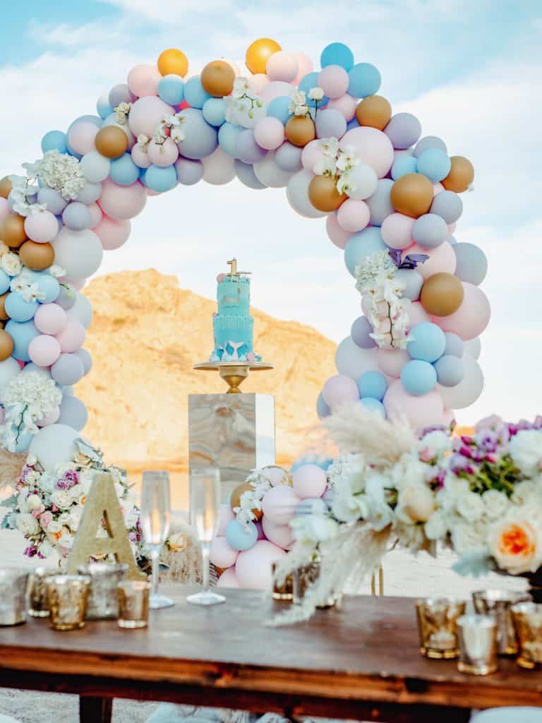 Balloons, blue cake, and party table on the beach