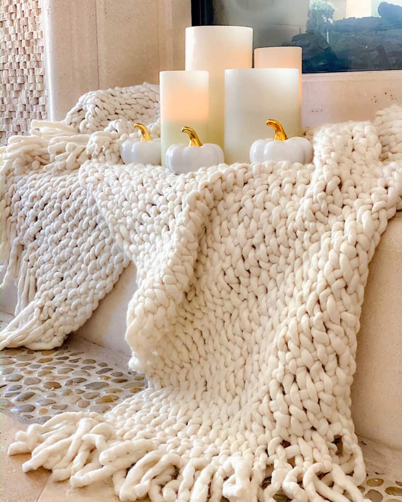 Stylish fall decor ideas: white throw, candles and ceramic pumpkin decoration