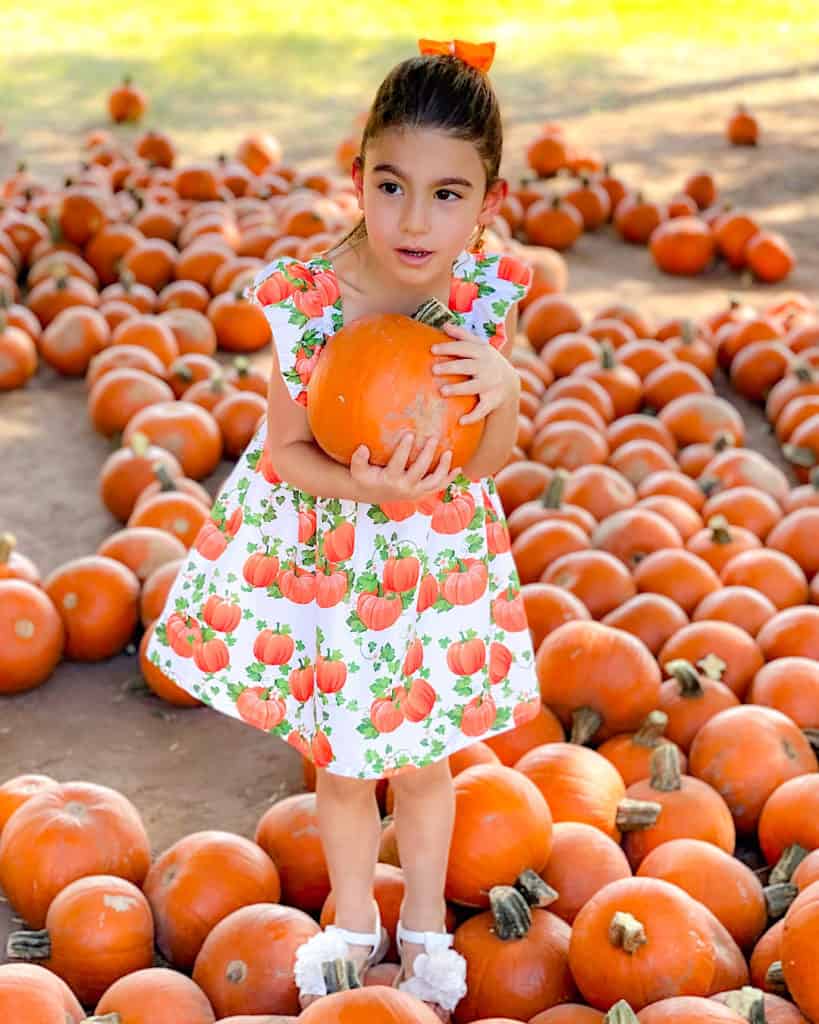 My eldest in a cute pumpkin dress at the pumpkin patch: top tip, take a change of clothes!