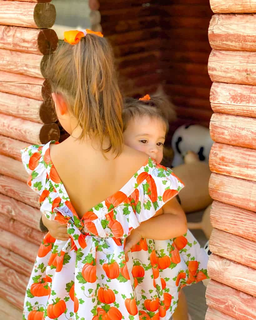 Sisters in matching dresses having a great day out at the pumpkin patch