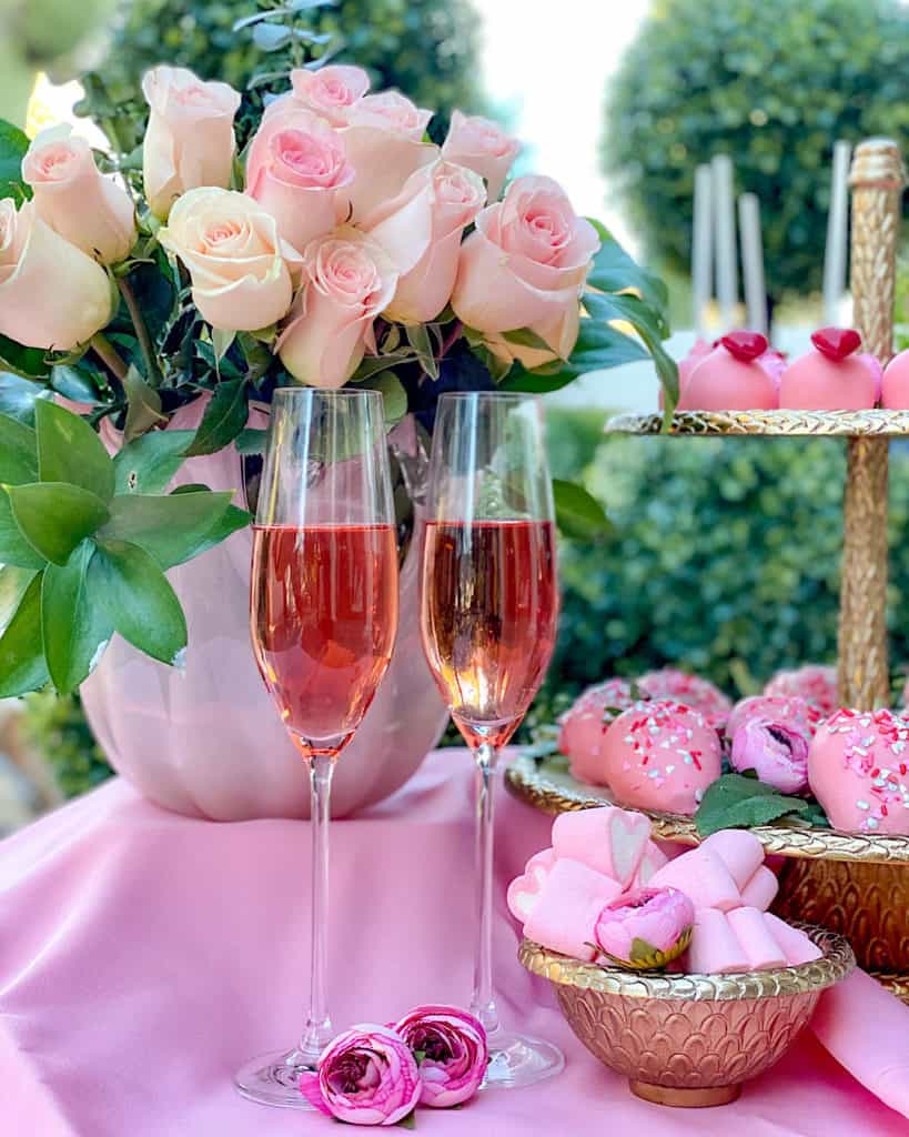 Pink roses, pink champagne and bowls of sweets on a Valentine’s Day Dessert Table