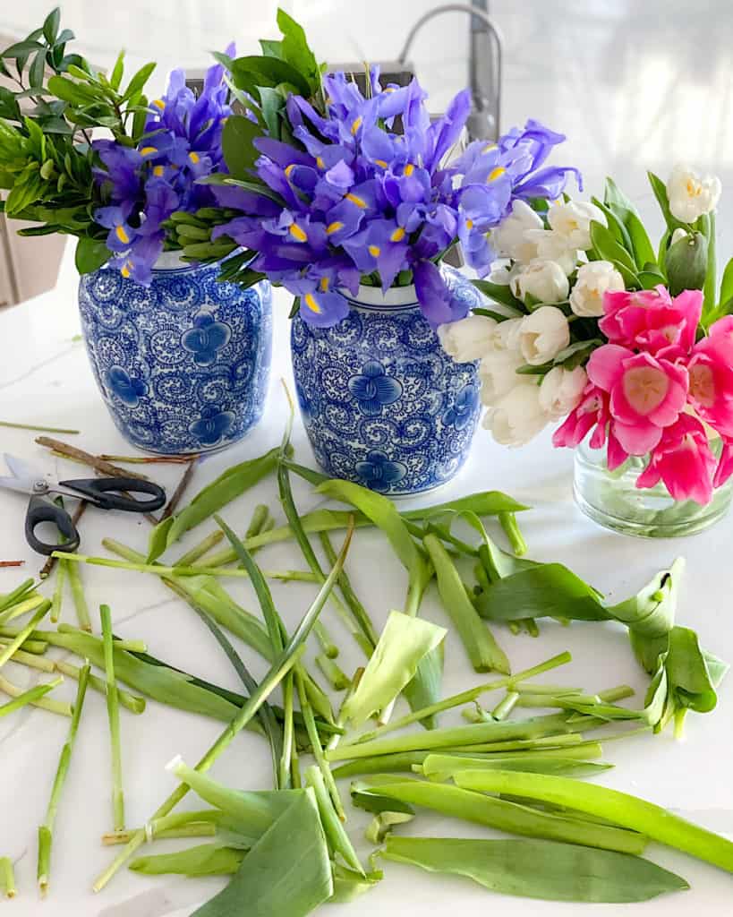 Irises in blue vase, tulips in clear vase. 