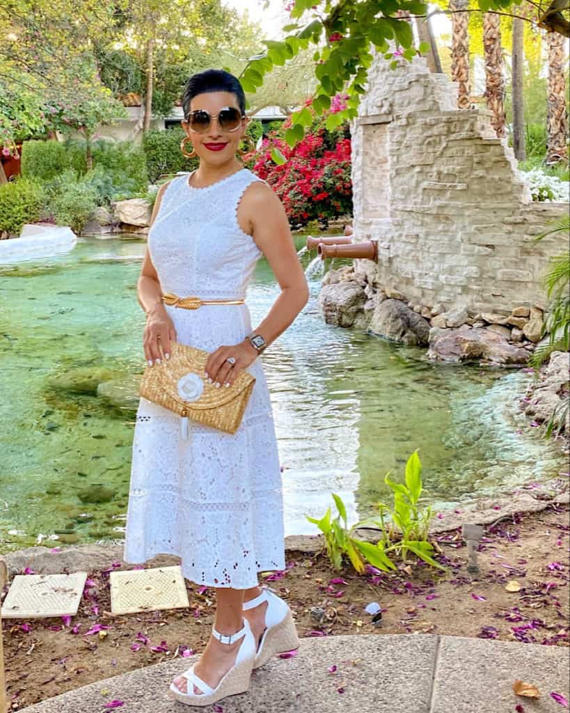 Woman wearing white dress, white wedge sandals and clutch bag