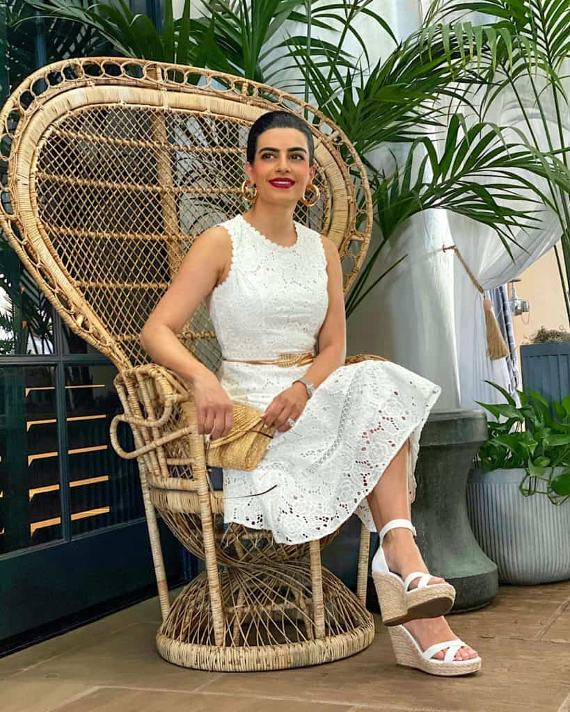 Woman wearing white dress, white wedge sandals and clutch bag