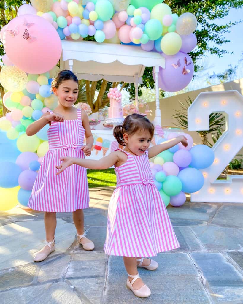 2 girls in striped dresses with balloons in background