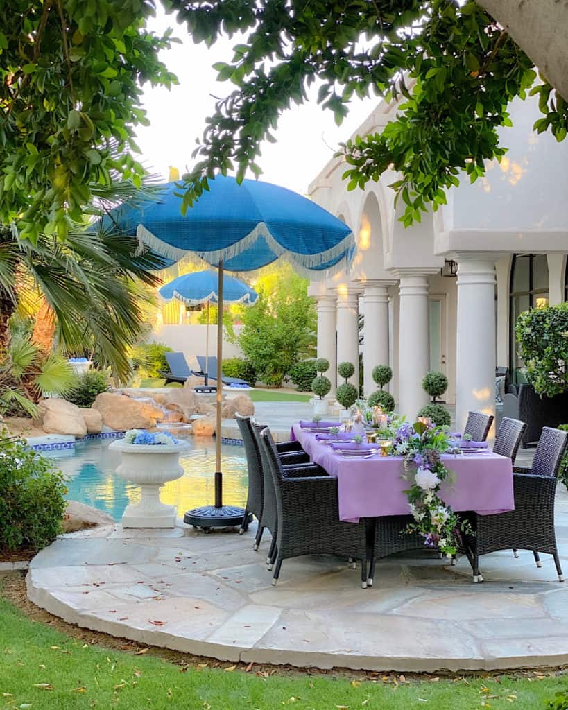 Purple and green decorated outdoor table by a pool.