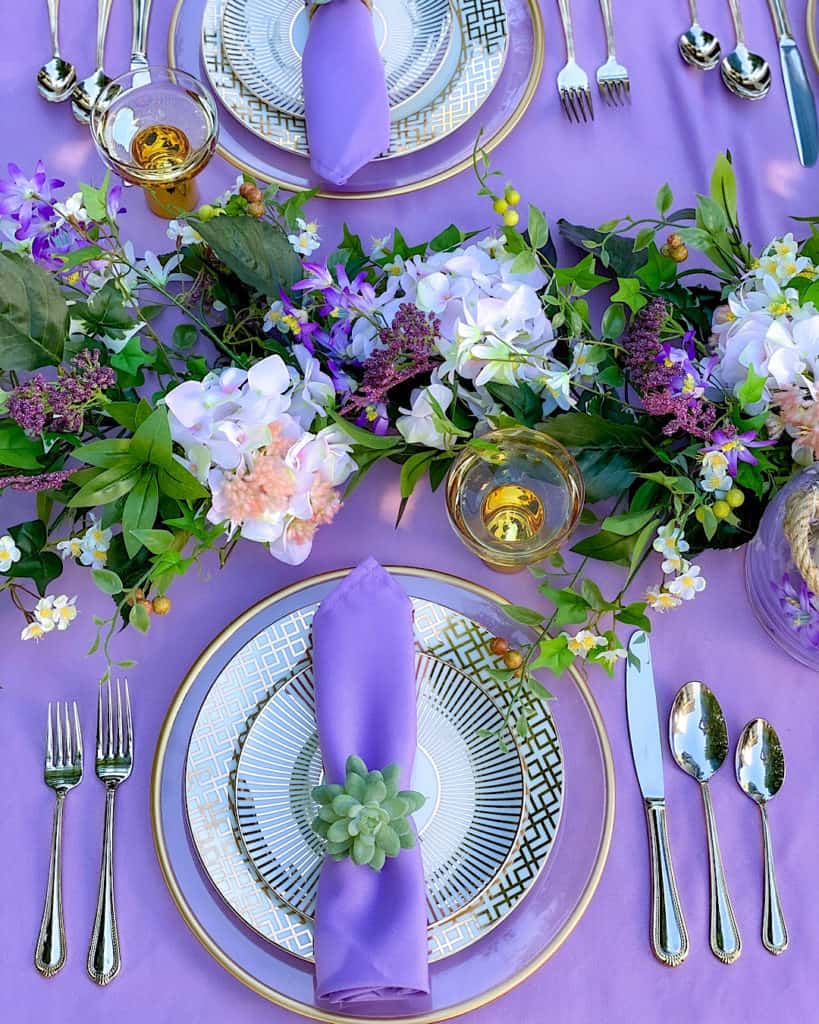 Purple napkin on flatware on purple tablecloth. Place setting for a spring outdoor brunch. 