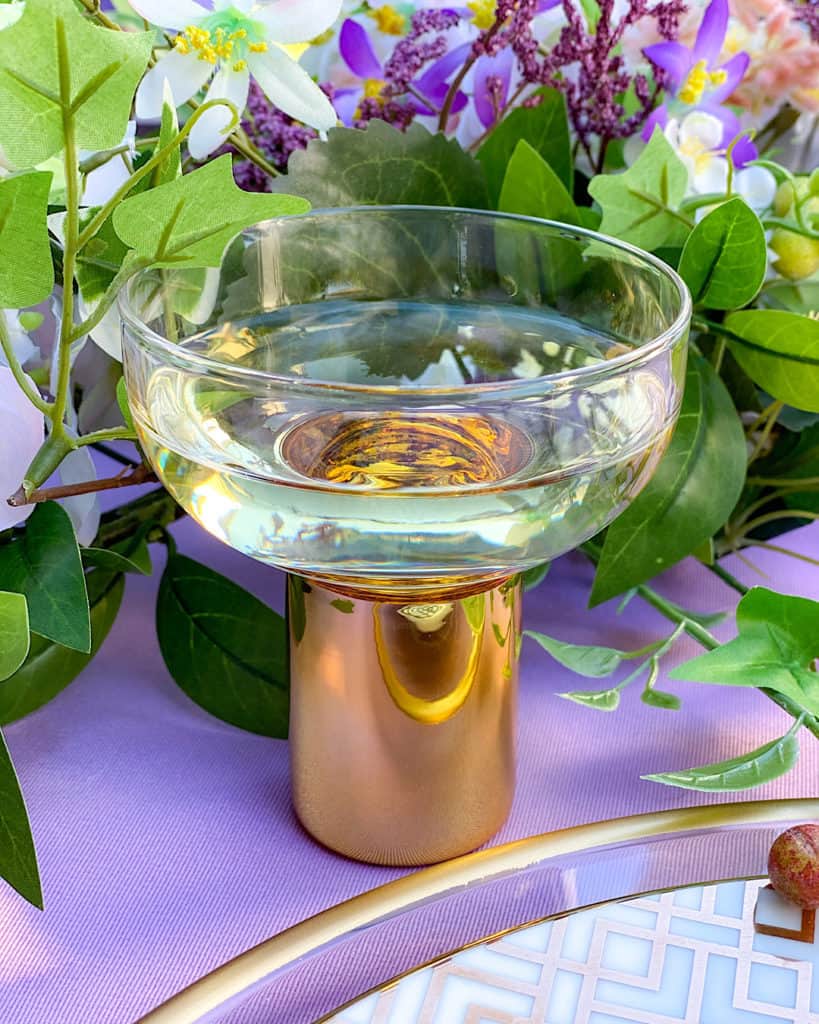 Glass and flowers on a purple tablecloth. 