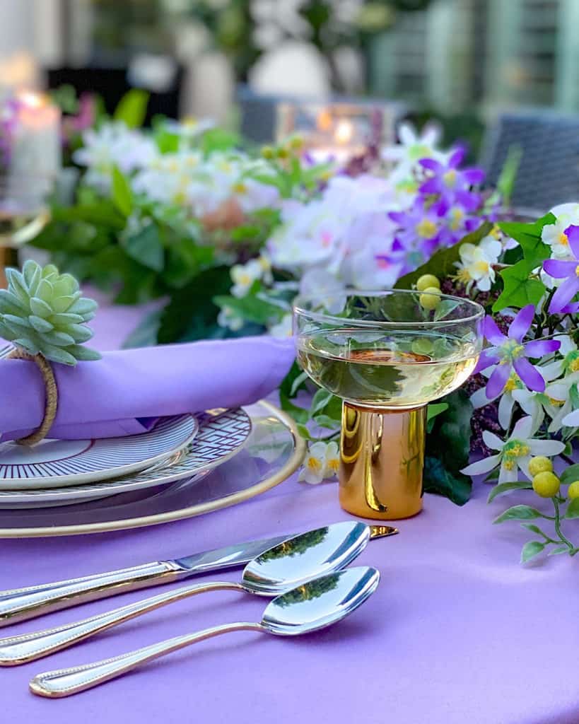 Cutlery, glass and place setting on a purple tablecloth. 