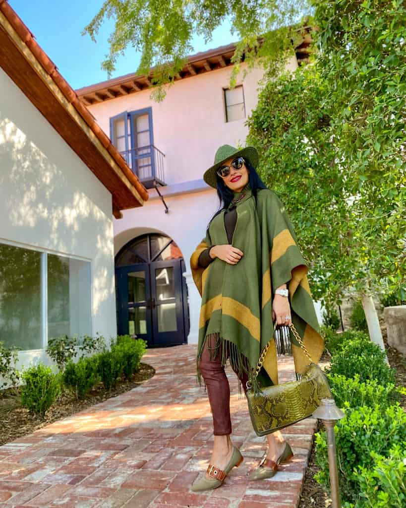 lady in green poncho and brown trousers with green bag. Fall fashion 2021