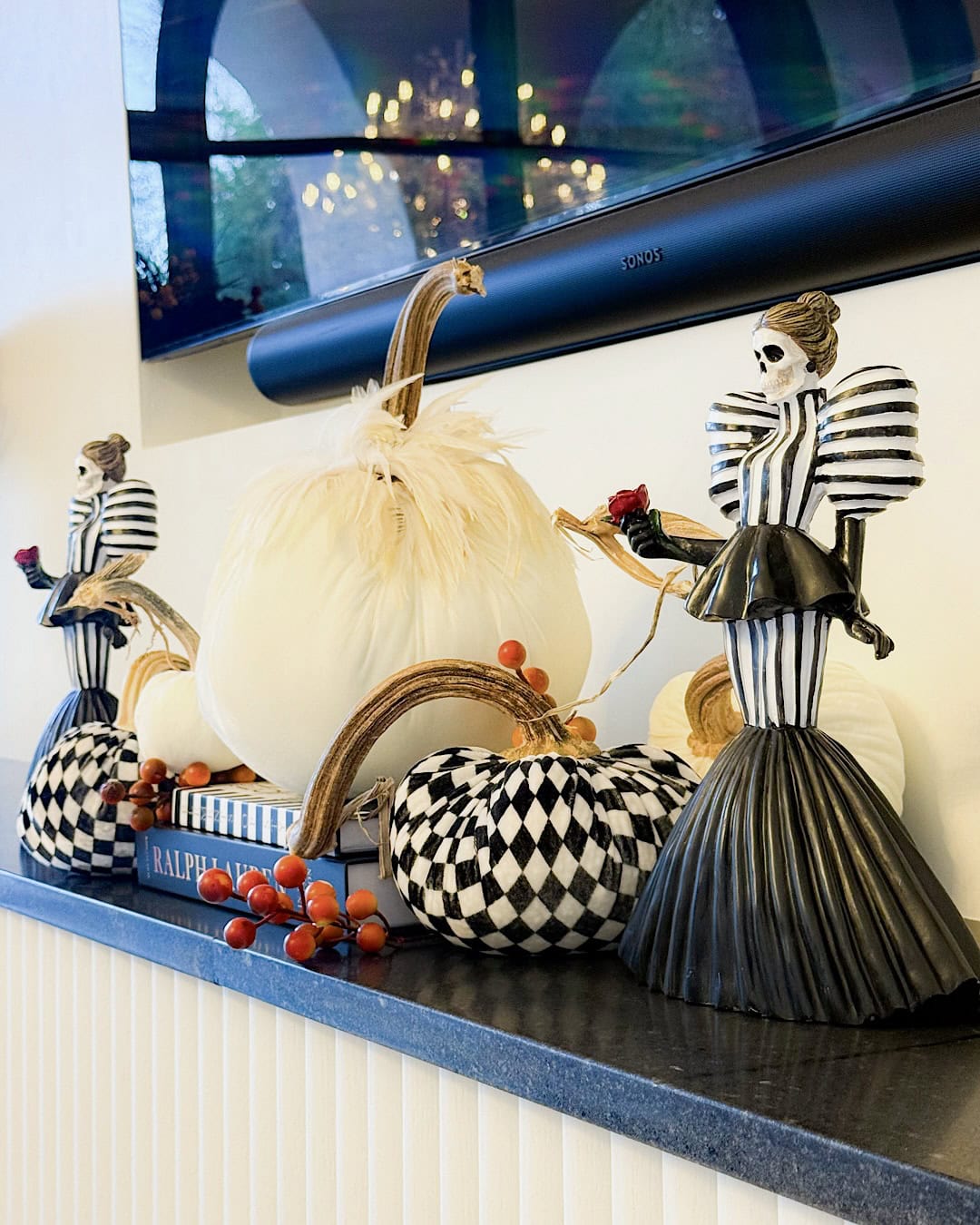 Black and white Halloween mantel with checkered pumpkins and skeleton figurines