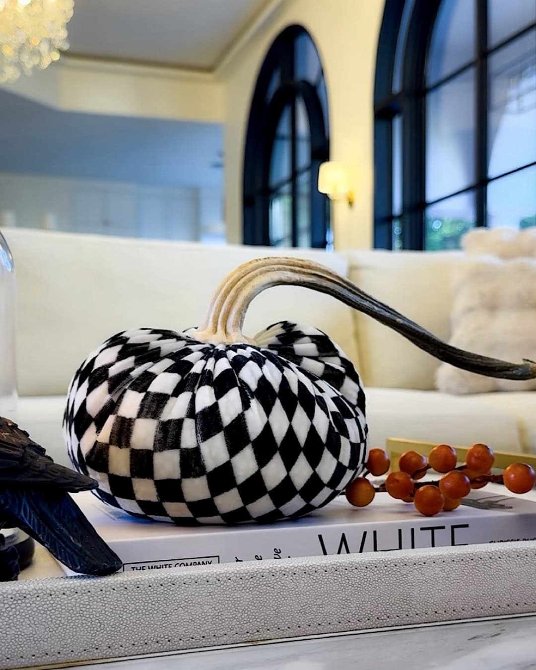 Classy Halloween decor with a black and white checkered velvet pumpkin on a coffee table