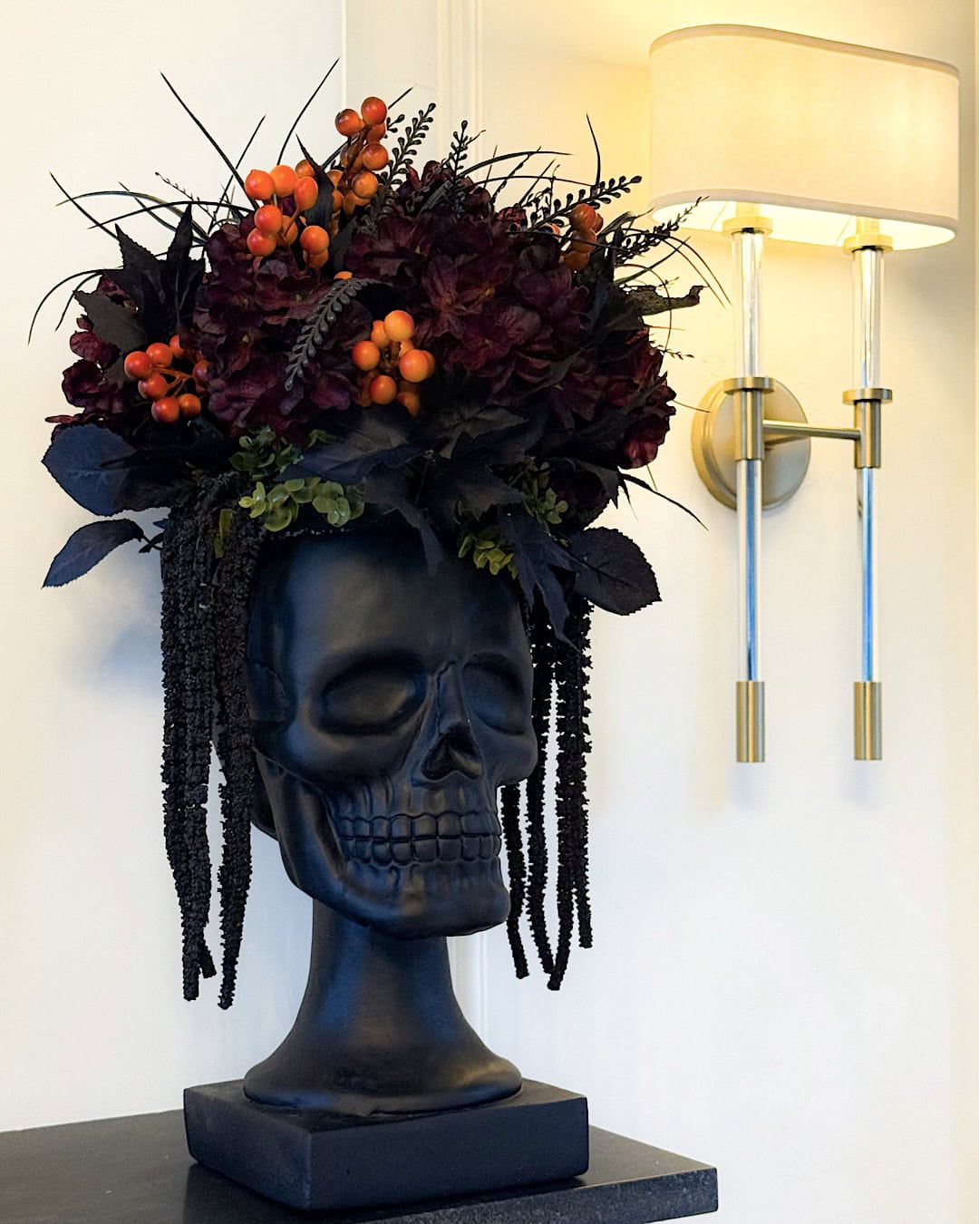 Elegant Halloween mantel decorations with a black skull planter and burgundy flowers