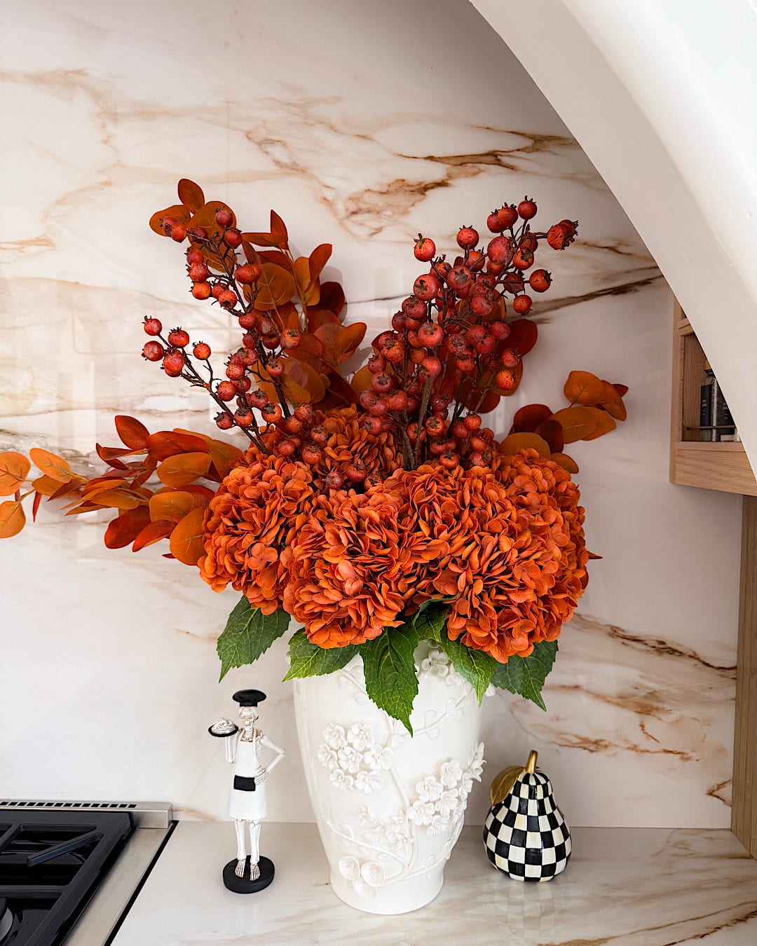  Halloween kitchen decor with a white vase of orange hydrangeas next to the range