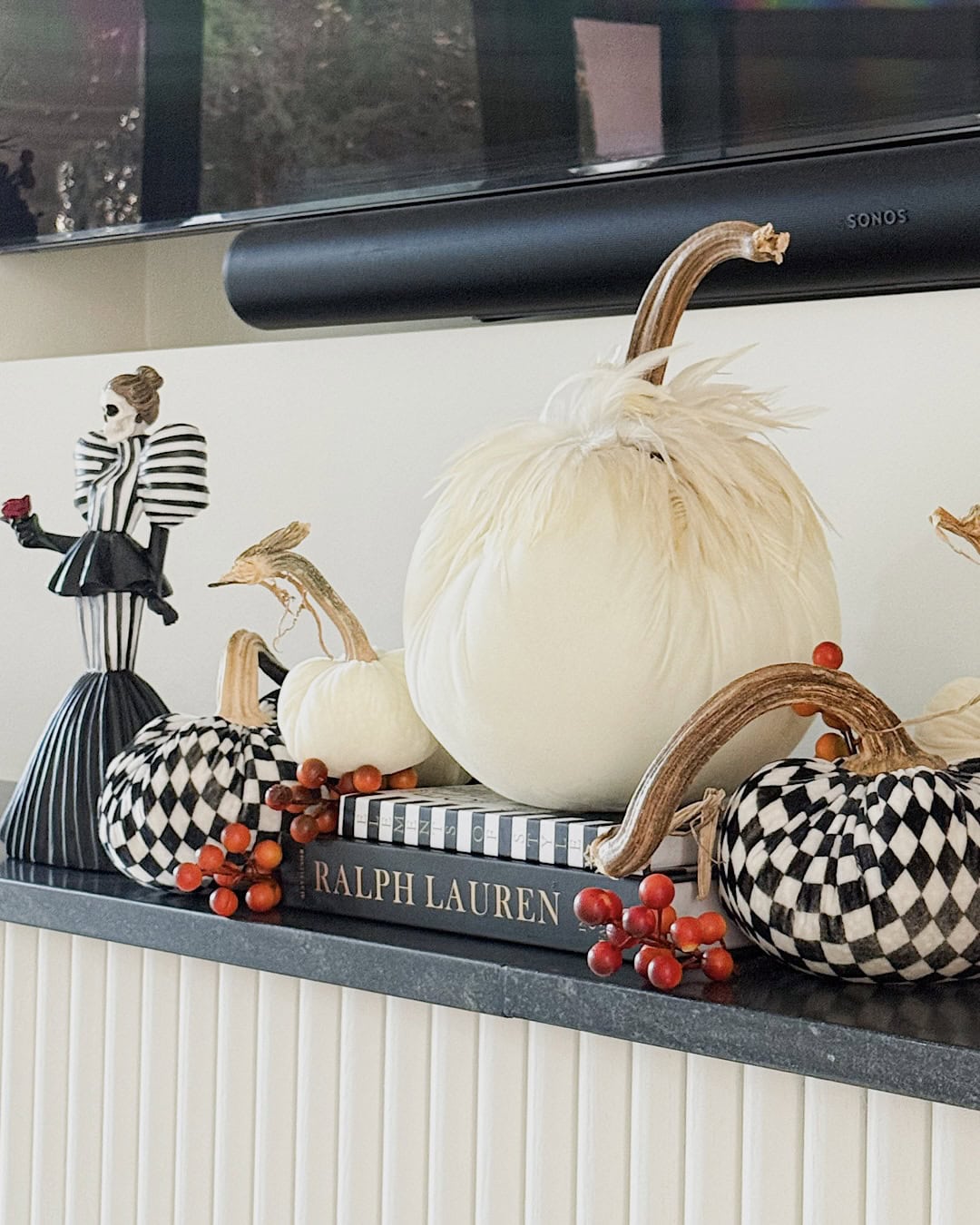 Halloween mantel decor with a large white velvet feather pumpkin on stacked books