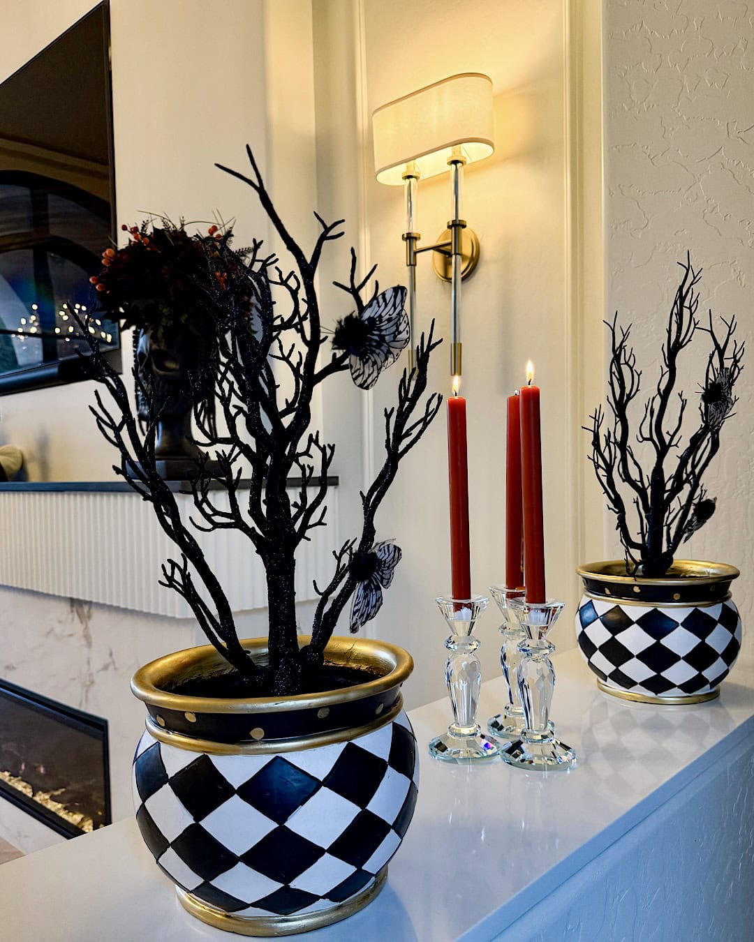 Halloween mantel decorating ideas with black branches in checkered pots and red candles