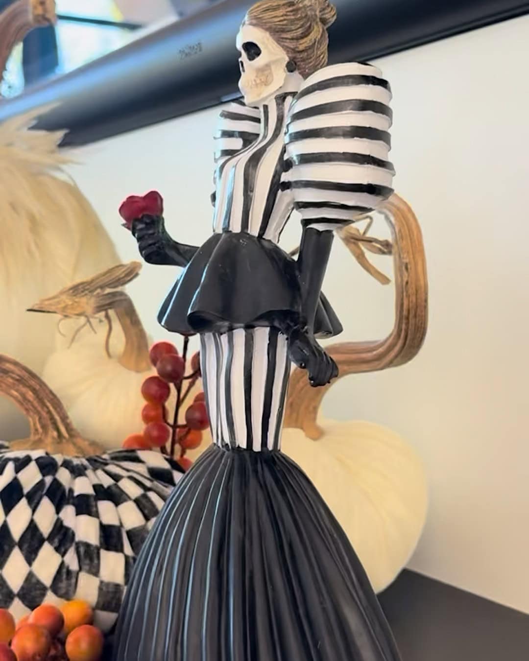 Halloween mantel with a black and white striped skeleton figurine holding a rose