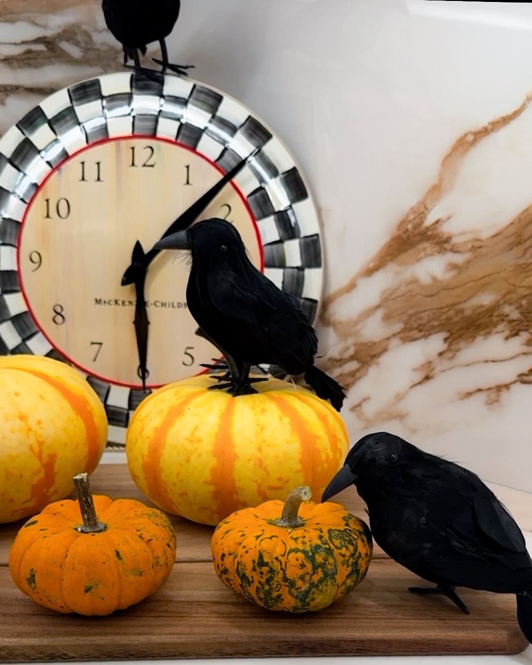 Spooky Halloween kitchen decor with black crows, mini pumpkins and a checkered clock