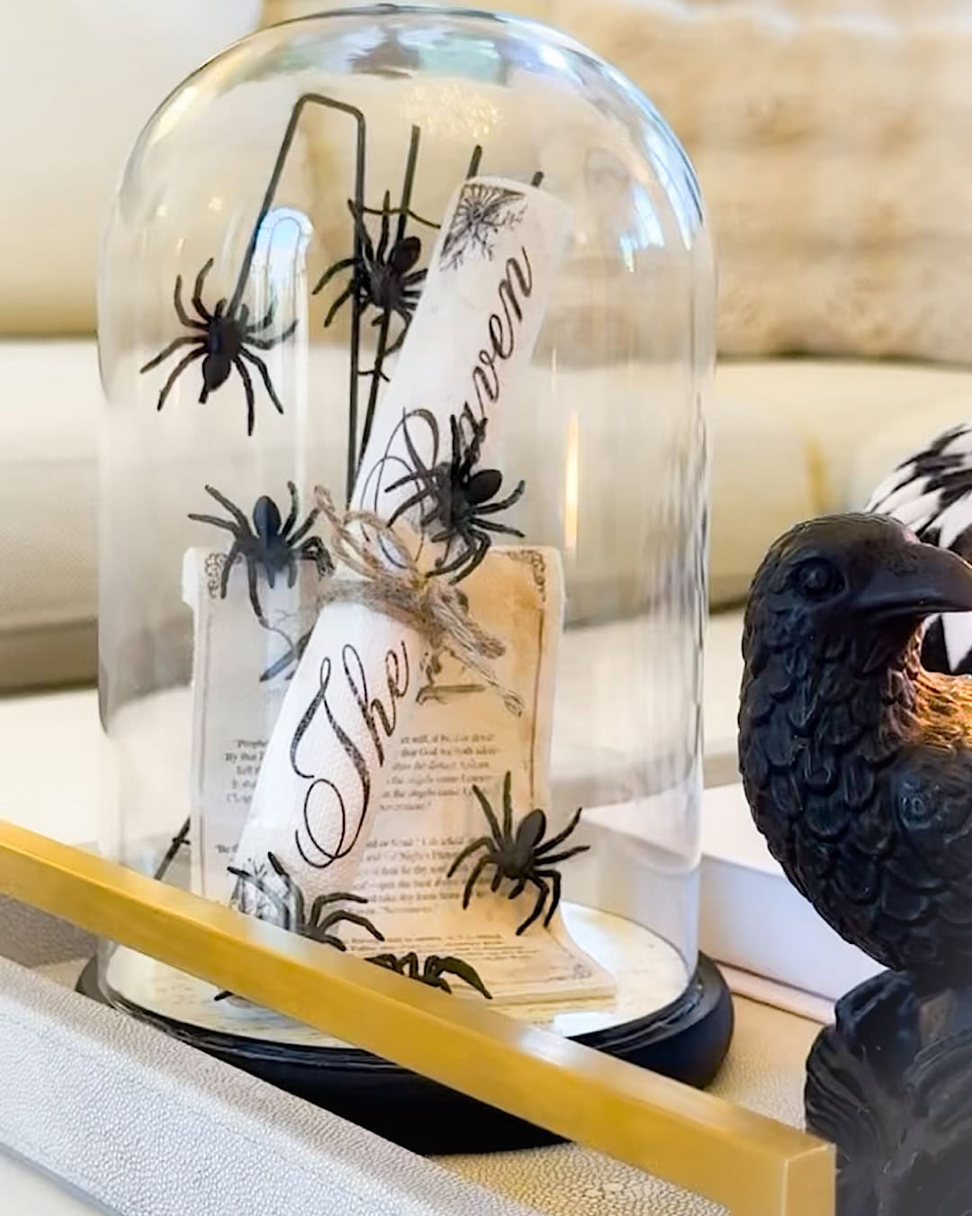 Spooky Halloween decor idea with a glass cloche, black spiders, and a raven