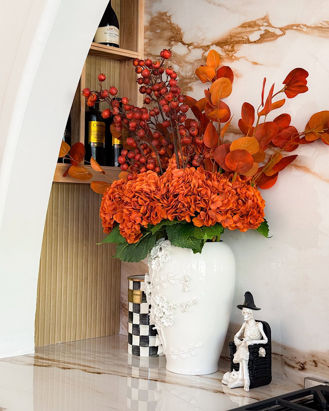 Spooky kitchen with orange hydrangeas in a white vase and a skeleton figurine